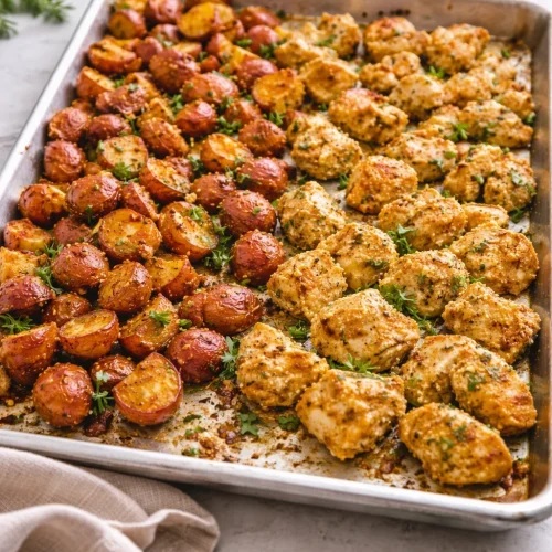 Baked garlic parmesan chicken with seasoned potatoes in a serving dish