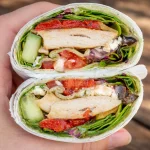 A variety of colorful healthy wraps filled with vegetables and proteins for lunch.