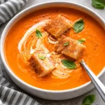 A bowl of simple tomato soup from scratch with fresh tomatoes and herbs.