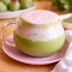 Iced matcha latte topped with creamy strawberry cold foam and fresh strawberries.