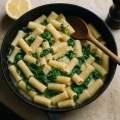 Skillet of penne in a glossy creamy garlic sauce with spinach and grated cheese